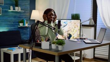 African blogger influencer putting on headset and smiling before recording blog, looking at camera. Social media content creator speaking during livestreaming, blogger discussing in podcast photo