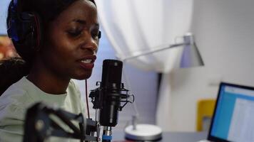 Close up of african blogger woman speaking at microphone during podcast using professional recording technology in home studio. Content creator making serires for channel, streaming online broadcast photo