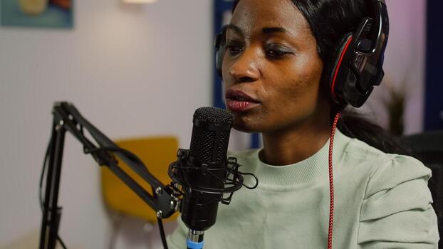 Portrait of african vlogger recording blog with modern equipment in studio podcast. Media star looking at laptop for digital broadcast having fun using technology to connect with audiences photo