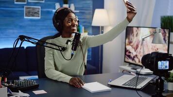 African woman blogger, vlogger portrait taking pictures of herself on smartphone. Content creator, on-air online production internet broadcast show host streaming live content for social media. photo