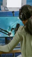 Black player wearing headphones talking with other players chatting while playing professional shooter games in online tournament. Gamer making online videogames with new graphics on powerful computer photo