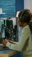 Black woman streamer playing space shooter videogames with joystick talking with teammates on streaming open chat. Cyber performing on RGB powerful computer in gaming room using professional equipment photo