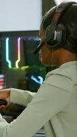 Pro african gamer playing online space shooter game on powerful computer using wireless controller and headset. Competitive cyber player woman performing videogame tournament use professional joystick photo