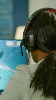 Closeup of competitive black woman player holding joystick playing space shooter game at powerful computer late night. Professional gamer using wireless controller for online gaming championship photo