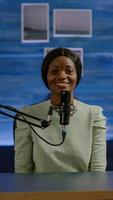 Portrait of african vlogger working in cozy studio, smiling at camera ready to start new podcast show. On-air online production internet broadcast show host streaming web content record digital blog photo