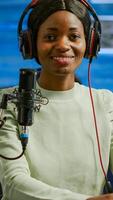 Portrait of african smiling blogger looking at camera before starting live from home studio podcast. Content creator vlogger woman recording brodcast streaming online content for social media photo