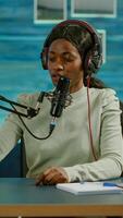 Black blogger woman recording for her blog in home studio reading messages checking sound on mixer. On-air online production internet broadcast show host streaming live content for social media photo