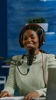 Woman african vlogger recording to camera tutorial about lifestyle in home podcast studio during livestreaming. On-air online production internet broadcast show host streaming live content for social media photo