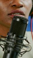 Close up of african influencer answering questions while talking into microphone for listeners. Speaking during livestreaming, blogger discussing in podcast wearing headphones. photo