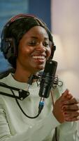 African vlogger recording blog using smartphone with modern equipment in home studio podcast. Media star looking at camera for broadcast and having fun using technology to connect with audiences photo
