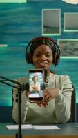 Black influencer in entertainment industry talking and checking sound during broadcast from home studio. On-air online production internet podcast show host streaming live content for social media photo