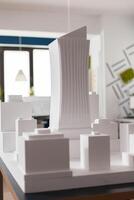 Closeup of 3D white foam architectural scale model of skyscraper building complex in architect modern office. Detail of urban development project on design table. photo