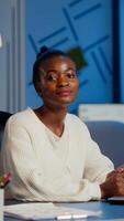Tired black woman manager looking at camera sighing after typing on laptop, working late at night in start-up financial business office. Focused employee doing overtime respecting deadline of project photo