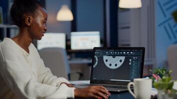 Excited black woman industry architect working on modern cad program overtime sitting in start-up office. Industrial engineer studying prototype idea on pc showing cad software on device display photo