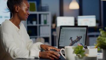 Black woman architect working in modern cad program overtime sitting at desk in start-up business office. Industrial employee studying prototype idea on laptop showing cad software on device display photo