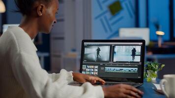 African videographer working at laptop from business office, editing and audio footage at night. Content creator using professional device modern technology network wireless processing film montage. photo