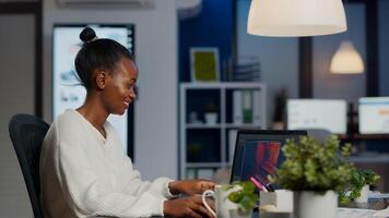Black freelancer game developer typing on keyboard developing new level of videogame. African pro player testing game over level interface in midnight from business office using laptop. photo
