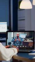 African businesswoman having corporate meeting with remotely paralyzed man using webcam of laptop sitting in start up business office working overtime. Manager talking on conference at midnight photo