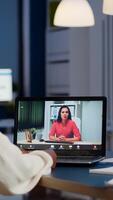 Dark skin manager woman talking with coworker during conference at midnight from business office planning financial strategy. Worker using wireless headphones discussing at virtual meeting photo