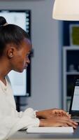 African architect analysing digital plans from laptop working in start-up business office overtime. Designer using cad software to design a 3D concept of buildings creating late at night photo