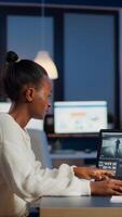 Black editor working overtime at new project editing audio film montage sitting in start-up business office. Woman content creator using professional laptop, modern technology, network wireless photo