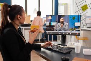 Businesswoman having delivery takeaway lunch meal order during takeout lunchtime at desk during online videocall meeting conference with remote manager. Entrepreneur eating pizza at workplace photo
