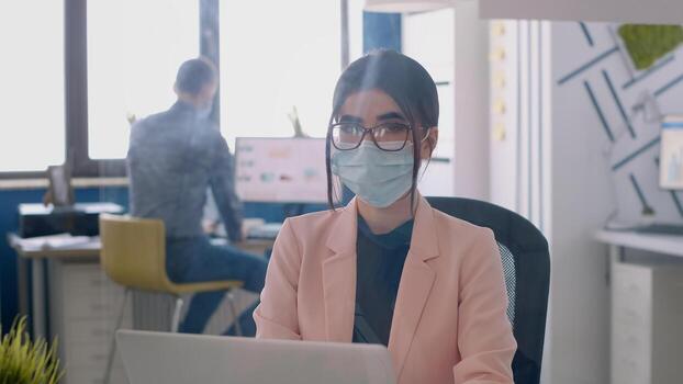 retrato de empresario trabajando en ordenador portátil computadora analizando financiero gráficos mientras vistiendo protector cara máscara a evitar infección con coronavirus. compañeros de trabajo respecto a social distanciamiento foto