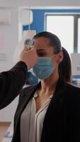 Business man with protective face mask checking collegues temperature using infrared thermometer to prevent virus infection. Coworkers keeping social distance to prevent coronavirus spread photo