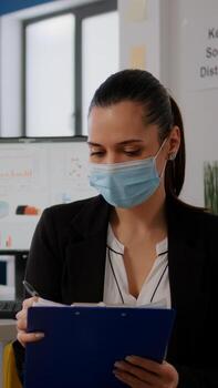 Pov of business woman with medical face mask working at communication project with team during online conference. Entrepreneur on web internet call in new normal corporate space photo
