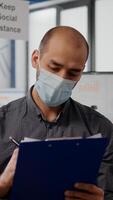 Pov of freelancer with protection face mask on zoom online call conference meeting. Businessman working in new normal office during coronavirus global pandemic, keep social distance signs on the wall photo