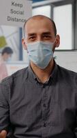 Pov entrepreneur man with protective face mask during zoom meeting call in new normal office. Freelancer talking into camera on remote online conference call photo
