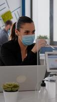 Close up of coworkers with face mask working together at financial project using tablet computer while sitting in company office. Team mantain social distance to avoid infection with covid19 photo