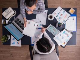 Top view of office workers meeting analyzing financial charts holding clipboard. Manager and employer discussing marketing strategy during briefing. Pointing at graphs. photo
