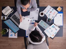 Top view of office workers meeting analyzing financial charts holding clipboard. Manager and employer discussing marketing strategy during briefing. Pointing at graphs. Business teamwork startup meeting photo