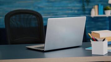 Close up of laptop computer placed on modern working desk in empty home office with blue furniture and walls. Workplace with nobody in it, place of work, workspace concept, pretty simple decor photo