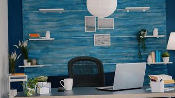 Empty home office with computer in a beautiful, spacious living room interior with blue furniture and walls. Workplace with nobody in it, place of work, workspace concept, pretty simple modern decor photo