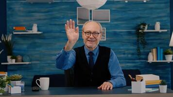 POV of elderly aged man waving during a conference with business partners working from home. Senior person using internet online chat technology webcam making virtual meeting call connection photo
