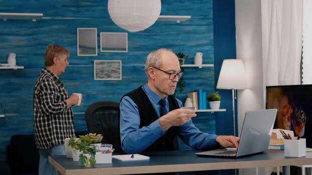 retirado hombre haciendo en línea pago utilizando crédito tarjeta en ordenador portátil trabajando desde hogar. mayor persona compras en línea, pago facturas, haciendo comercio electrónico actas utilizando moderno tecnología vía Internet foto