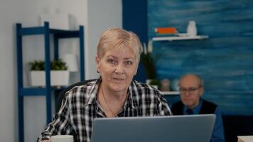 POV of elderly aged woman waving during a conference with business partners working from home. Senior person using internet online chat technology webcam making virtual meeting call connection photo