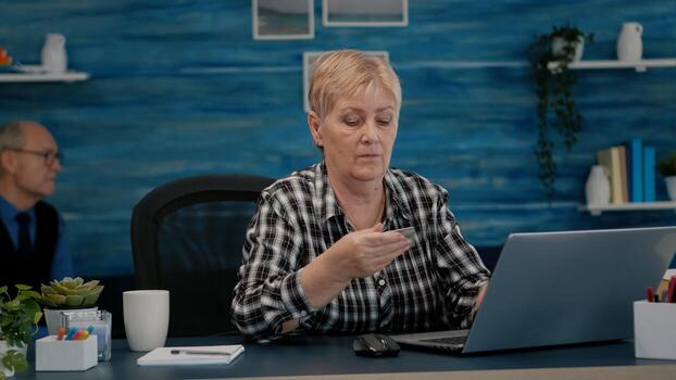 mayor mujer haciendo en línea pago utilizando crédito tarjeta en ordenador portátil trabajando desde hogar. retirado antiguo persona compras en línea, pago facturas, haciendo comercio electrónico actas utilizando moderno tecnología vía Internet foto