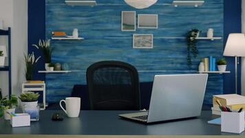 Empty workspace of freelancer worker with laptop computer on desk and cup of coffee. Interior of empty bright workspace with blue furniture and walls, beautiful decorated, cozy apartment photo