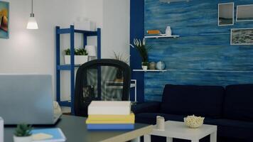 Office living room with nobody in it, place of home work, workplace indoors concept with open laptop on desk. Interior of empty bright workspace with blue furniture and walls, beautiful decorated. photo