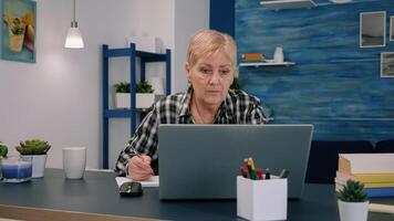 grave maduro medio Envejecido negocio mujer utilizando ordenador portátil mecanografía correo electrónico y escritura en computadora portátil, trabajando a hogar oficina, enfocado mayor antiguo dama buscando información en Internet o comunicado en línea foto