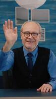 POV of elderly aged man waving during a conference with business partners working from home. Senior person using internet online chat technology webcam making virtual meeting call connection photo