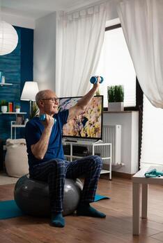 Jubilación mayor hombre sentado en aeróbicos suizo pelota levantamiento mano estirar brazo músculo haciendo aptitud ejercicio. pensionista hacer ejercicio cuerpo músculos utilizando pesas formación muscular resistencia foto