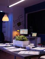 Modern empty business corporate office meeting room is ready for businesspeople late at night. In background on conference table standing company financial documents with economy graphs photo