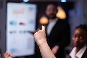 Selective focus of businesswoman asking question during branstorming, late at night in the office. Diverse teamwork working at management presentation in meeting room. photo