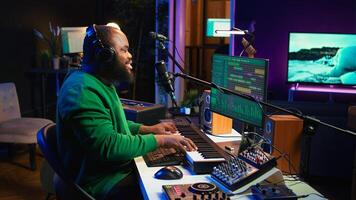 Young artist playing piano keys and singing song on microphone, composing his new music and mixing the tracks on digital interface. Producer technician composing melody with gear. Camera B. photo