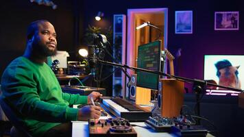 Composer writes verses and ideas to develop original song in home studio before recording new audio files. Songwriter using musical equipment and his imagination, artist composes music. Camera B. photo