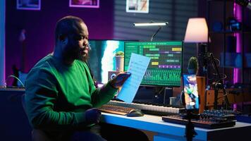 Artist pointing at musical sheet notation to explain notes on piano, teaching people to play synthesizer in home studio. Composer musician playing midi controller during online master class. Camera A. photo